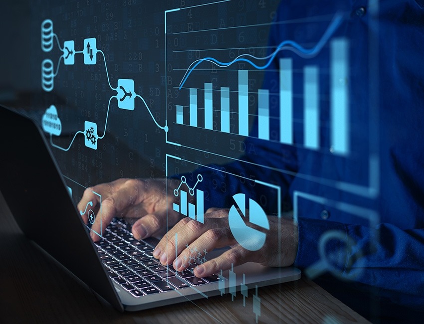 A person is using a computer while charts and system networks are displayed over the image.